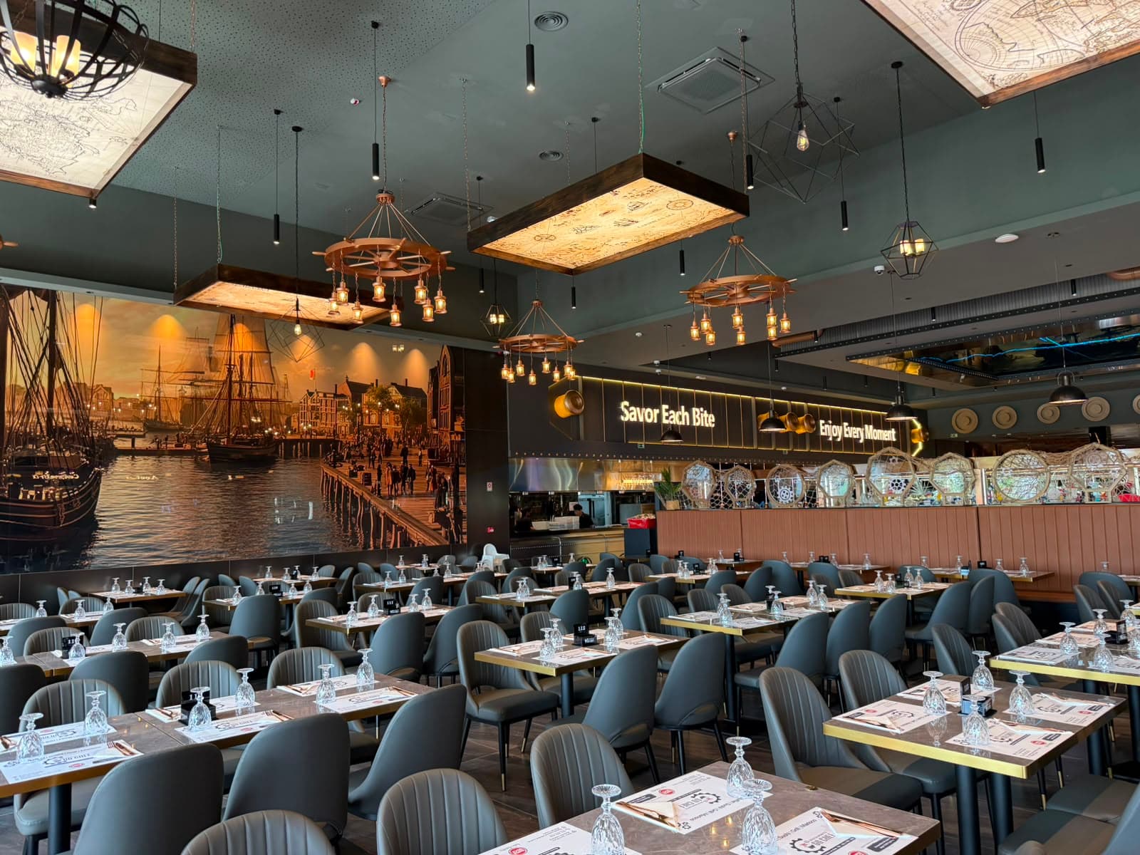 Restaurante amplo com mesas, iluminação quente e balcão ao fundo